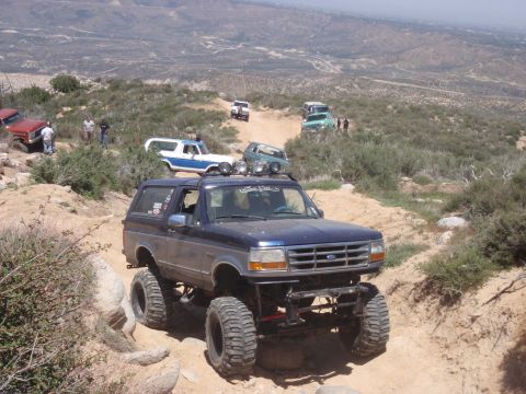 1978 Ford Bronco - Several off-road vehicles navigate a steep, dusty mountain path.