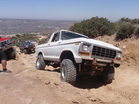 1978 Ford Bronco - This lifted 1978 Ford Bronco navigates a challenging off-road course with other vehicles visible in the background.