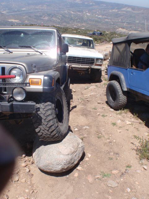 1978 Ford Bronco - Three off-road vehicles, including a 1978 Ford Bronco, navigate a rocky trail in a mountainous area.
