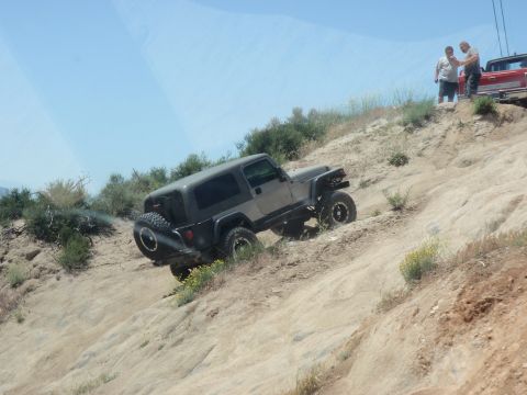 1978 Ford Bronco - A Jeep Wrangler TJ navigates a steep, dusty incline with onlookers and another vehicle nearby.