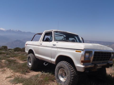 1978 Ford Bronco - This 1978 Ford Bronco, equipped with a roll cage, is seen parked on a hillside with mountains in the background.