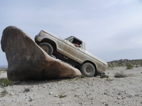 1978 Ford Bronco - A white 1978 Ford Bronco navigates a challenging rocky terrain in a desert environment.