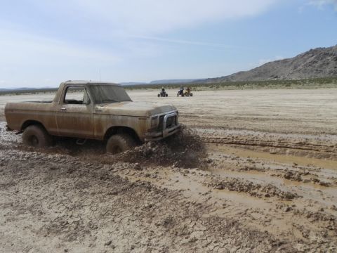 1978 Ford Bronco - Ford Bronco navigating a muddy off-road track in a dry, desert landscape.