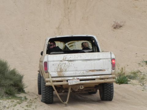 1978 Ford Bronco - White 1978 Ford F-150 pickup truck with two occupants driving on a dusty, off-road trail.