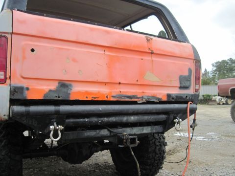 1978 Ford Bronco - Rear view of an orange SUV with visible body damage and an aftermarket bumper.