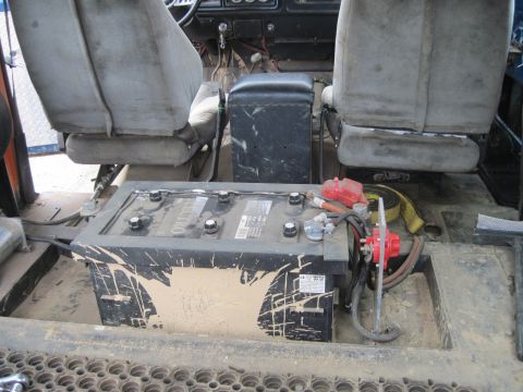 1978 Ford Bronco - The interior of the vehicle shows a large, dirty battery with visible wiring and a yellow strap.