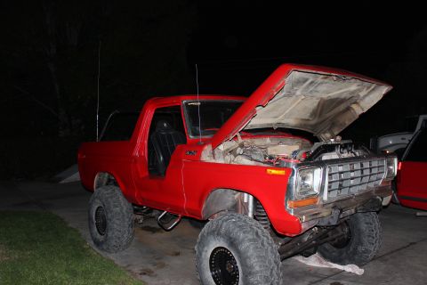 1978 Ford Bronco - A red 1978 Ford Bronco is shown with its hood open, revealing the engine bay and modified suspension.