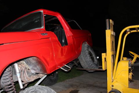 1978 Ford Bronco - Forklift lifting a red 1978 Ford Bronco. The vehicle appears to be modified.