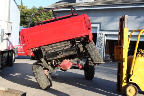 1978 Ford Bronco - Forklift lifting the rear of a red 1978 Ford Bronco. Roll cage is installed.
