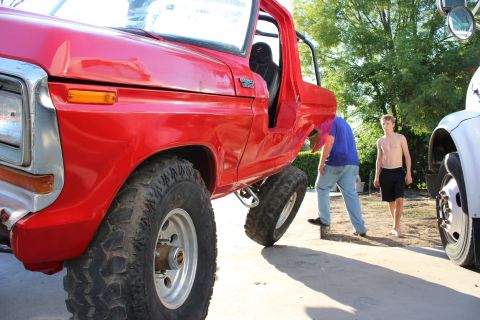 1978 Ford Bronco - A red first-generation-era Ford Bronco with its doors and top removed, showing a roll bar, black bucket seat, and 'BRONCO' emblem, sits on…