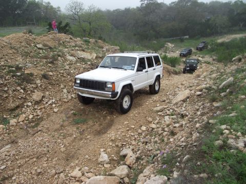 1989 Ford Bronco - Multiple Jeep Cherokees navigate a challenging rocky trail during an off-road excursion.
