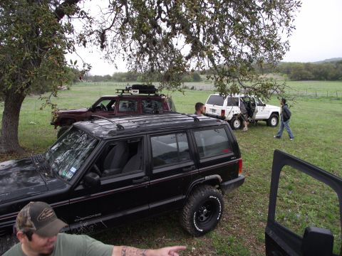 1989 Ford Bronco - Three Jeep SUVs are parked in a field, with people interacting around them.