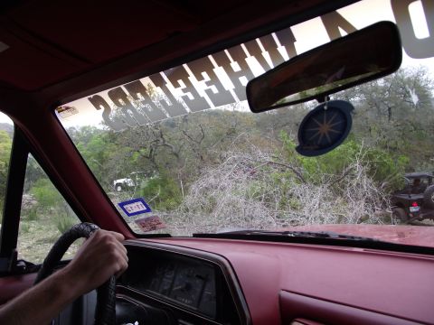 1989 Ford Bronco - Driving off-road through a wooded area, with another vehicle visible ahead.