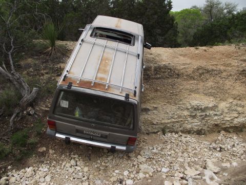 1989 Ford Bronco - This SUV is parked precariously on a rocky incline, its rear visible.
