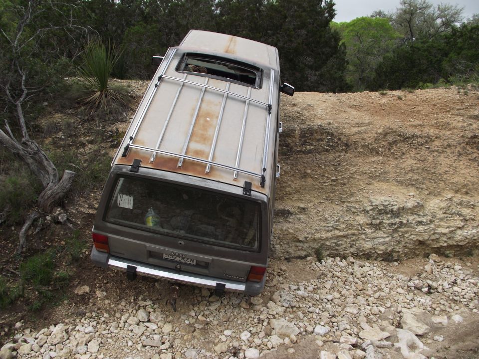 Brown SUV with roof rack tilted on rocky terrain
