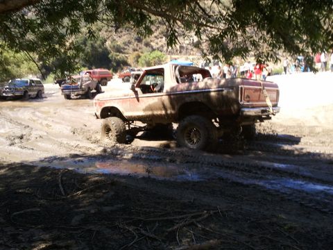 1978 Ford Bronco - Several off-road vehicles are stuck in deep mud, with one Bronco prominently featured.