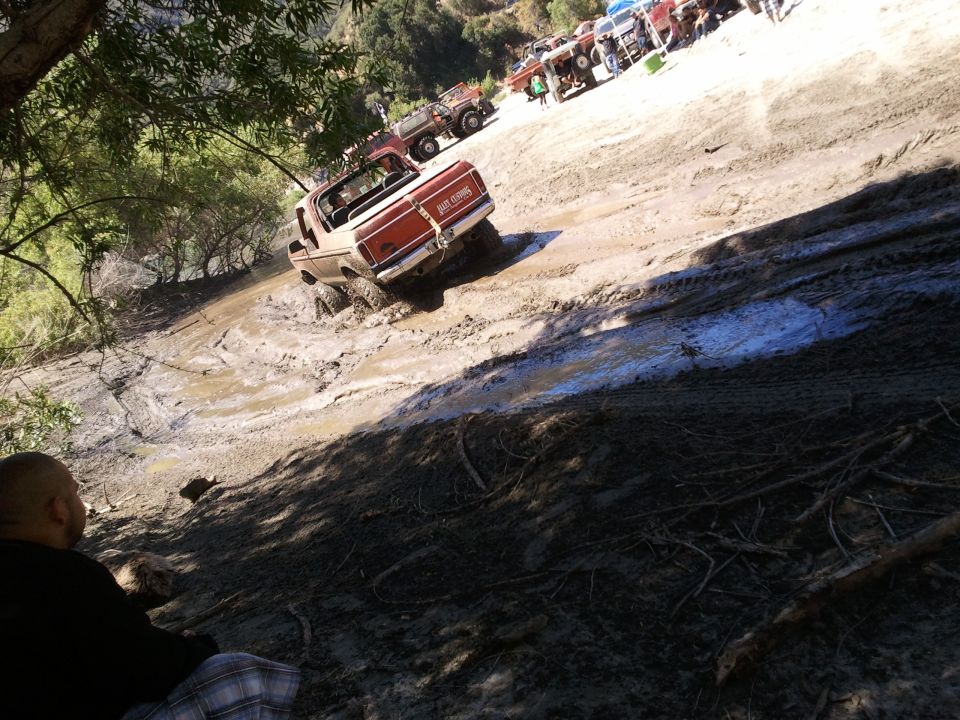 1978 Ford Bronco navigating a muddy hill with other off-road vehicles in the background