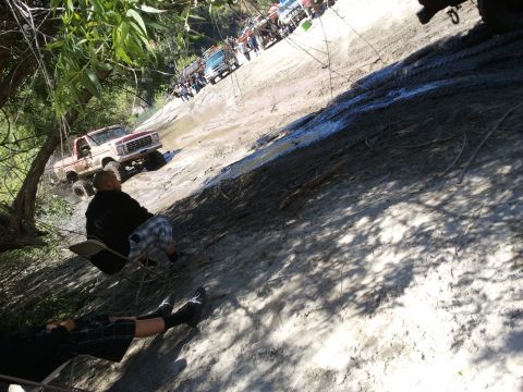 1978 Ford Bronco - Several off-road vehicles, including a 1979 Ford F-150, navigate a steep, muddy incline with onlookers present.
