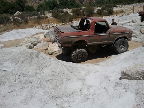 1978 Ford Bronco - A red 1978 Ford Bronco navigates a challenging rocky trail, showing its off-road capabilities.