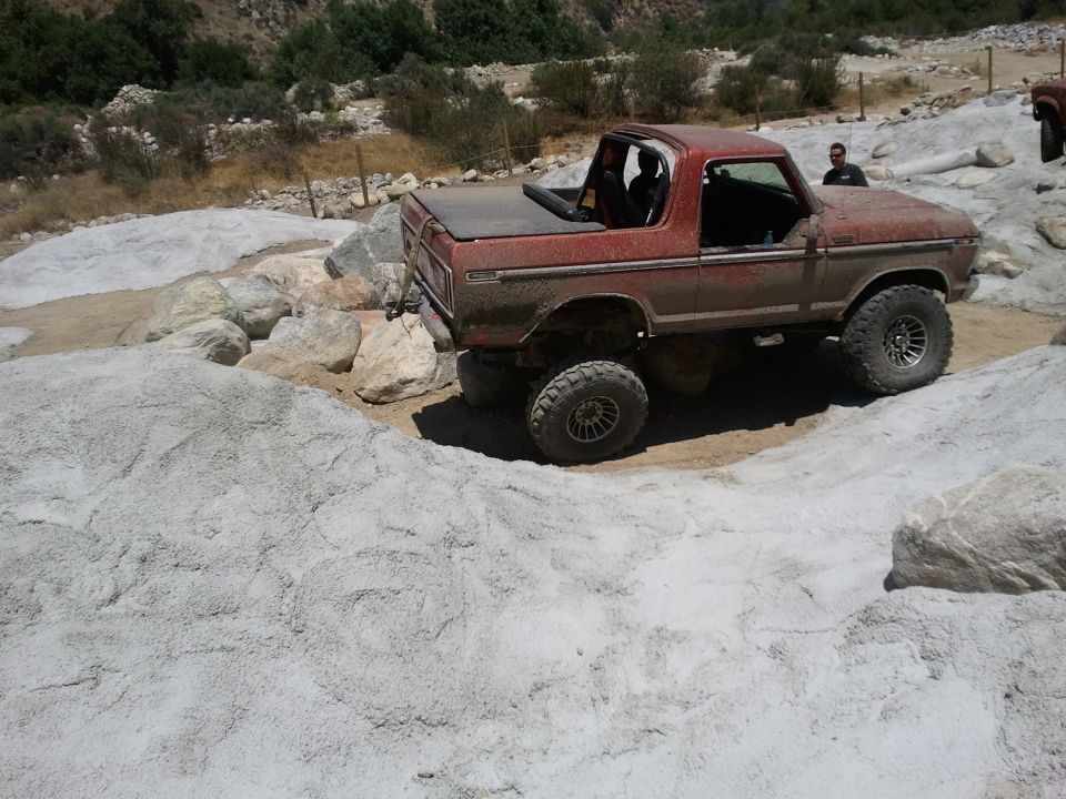 Red 1978 Ford Bronco on rocky terrain, side view, with a soft top