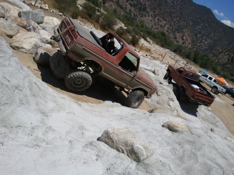 1978 Ford Bronco - A red 1978 Ford Bronco navigates a steep, rocky incline, with another vehicle visible in the background.