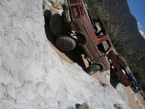 1978 Ford Bronco - Off-road trucks navigate a steep, rocky terrain. The lead vehicle appears to be a 1978 Ford Bronco.