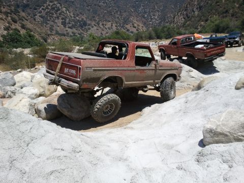 1978 Ford Bronco - A red Ford Bronco navigates a rocky trail with another truck visible in the background.