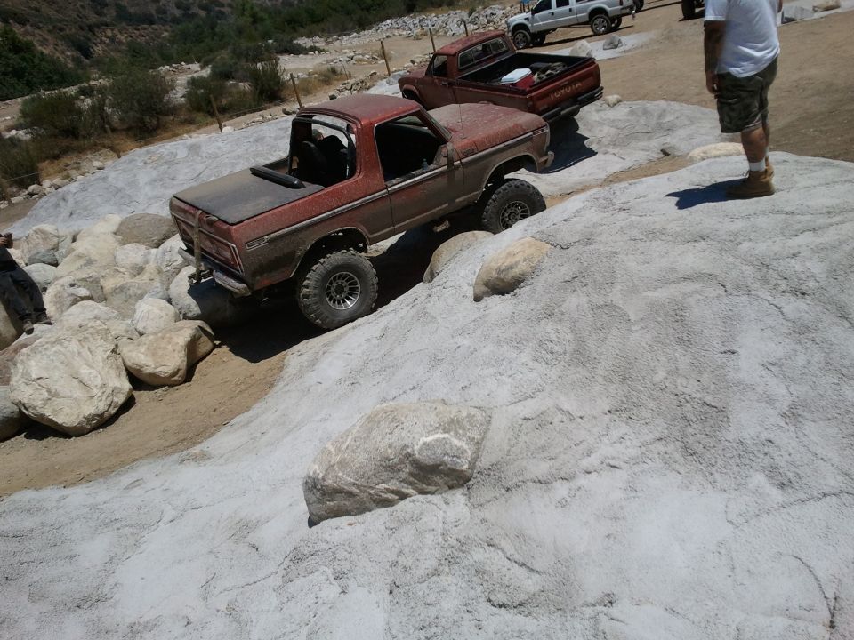 1978 Ford Bronco climbing rocks, red exterior, lifted suspension