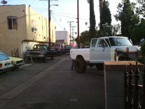 1978 Ford Bronco - Multiple pickup trucks and a car are parked in a narrow alleyway.