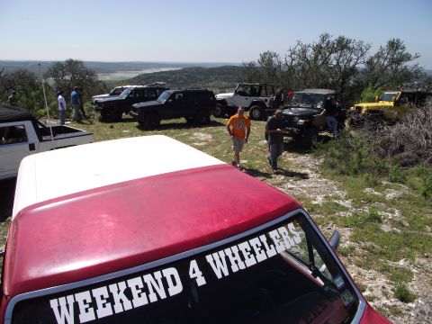 1989 Ford Bronco - A group of off-road vehicles are gathered on a hilltop overlooking a valley on a sunny day.