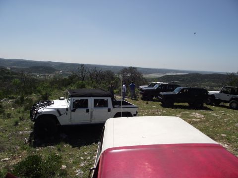 1989 Ford Bronco - A group of SUVs, including a white Hummer H1 pickup, are parked on a scenic overlook.