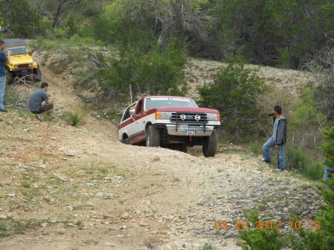 1989 Ford Bronco - Two vehicles navigate a challenging off-road trail with onlookers present.