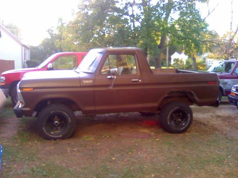 1979 Ford Bronco - Side view of a brown 1979 Ford Bronco with a red pickup truck behind it.