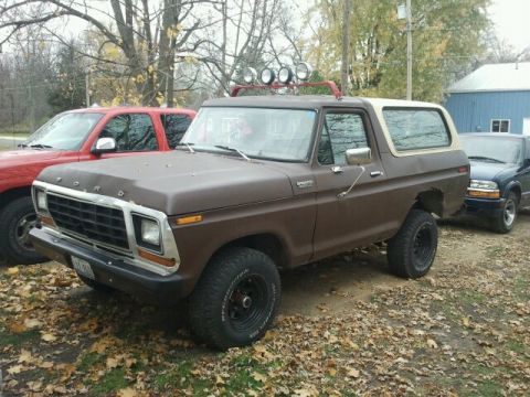 1979 Ford Bronco - Brown 1978 Ford Bronco with aftermarket lights on roof rack is parked outdoors.