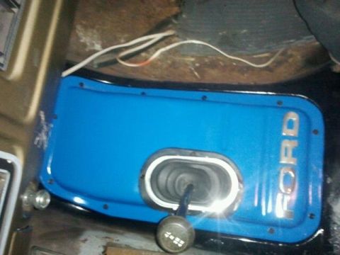 1979 Ford Bronco - Close-up of a blue Ford shifter plate with chrome lettering and a black shift knob.
