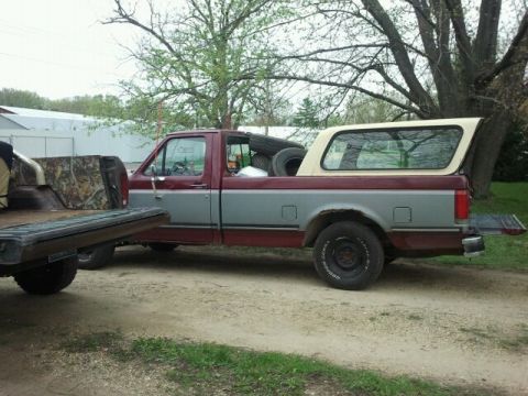 1979 Ford Bronco - This Ford pickup truck has a camper shell and spare tires loaded in the bed.