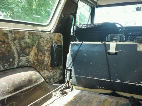 1979 Ford Bronco - The interior of a vehicle shows camouflage paneling and a speaker, with visible wear and tear.