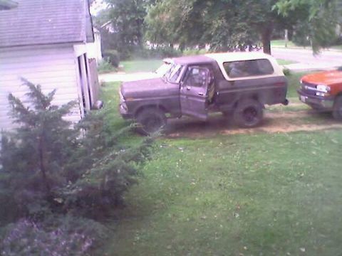 1979 Ford Bronco - A purple Ford Bronco is parked in a grassy yard next to a house, with another vehicle to its right.