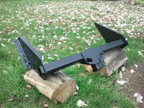1979 Ford Bronco - A black trailer hitch is shown resting on two wooden logs in a grassy area with fallen leaves.
