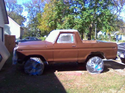 1979 Ford Bronco - A brown Ford Bronco is parked outside, with its windows taped off, suggesting it is being prepped for painting.