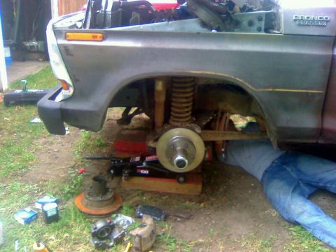 1979 Ford Bronco - A person works on the front suspension of a gray Ford Bronco, which appears to be a 1978 model.