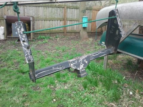 1979 Ford Bronco - A metal trailer hitch assembly is suspended by ropes in a backyard setting.