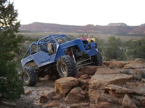 1979 Ford Bronco - Custom blue buggy navigates a rocky trail in a desert landscape.