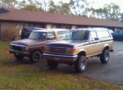 1979 Ford Bronco - Two Ford Broncos are parked in front of a motel. The tan Bronco is lifted.