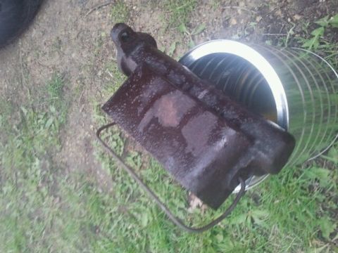 1979 Ford Bronco - A rusty metal component rests inside a cylindrical container on a grassy surface.