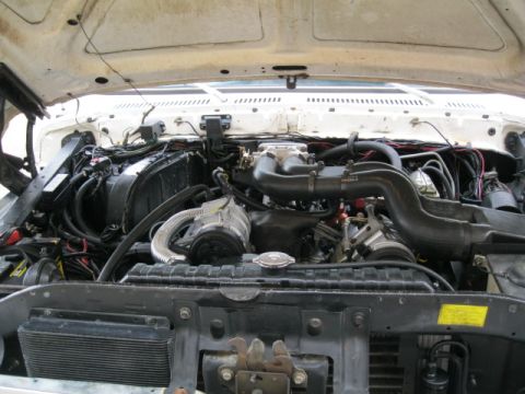 1978 Ford Bronco - The engine bay of a white vehicle is shown with the hood open, revealing the engine components and wiring.