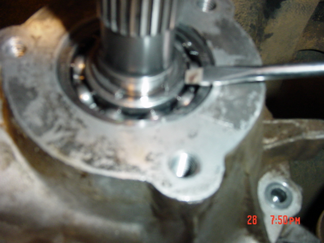 Disassembled transfer case showing splined output shaft, ball bearing and bolt holes on aluminum case