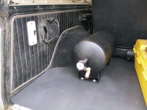 1978 Ford Bronco - The interior cargo area of a vehicle contains an air tank and a yellow toolbox.