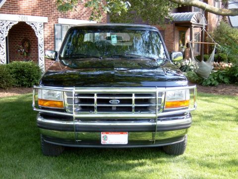 1995 Ford Bronco - Front view of a black Ford Bronco with a chrome grille guard, parked on a lawn in front of a house.