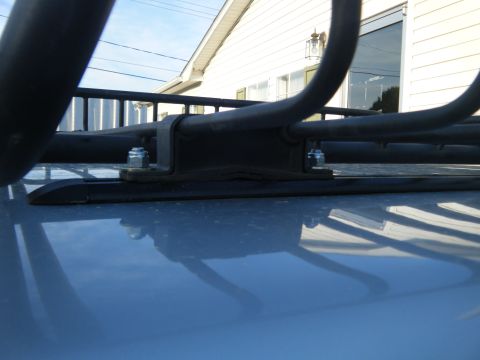 2003 Nissan Frontier - A close-up view of a roof rack's mounting hardware is shown against a bright sky.